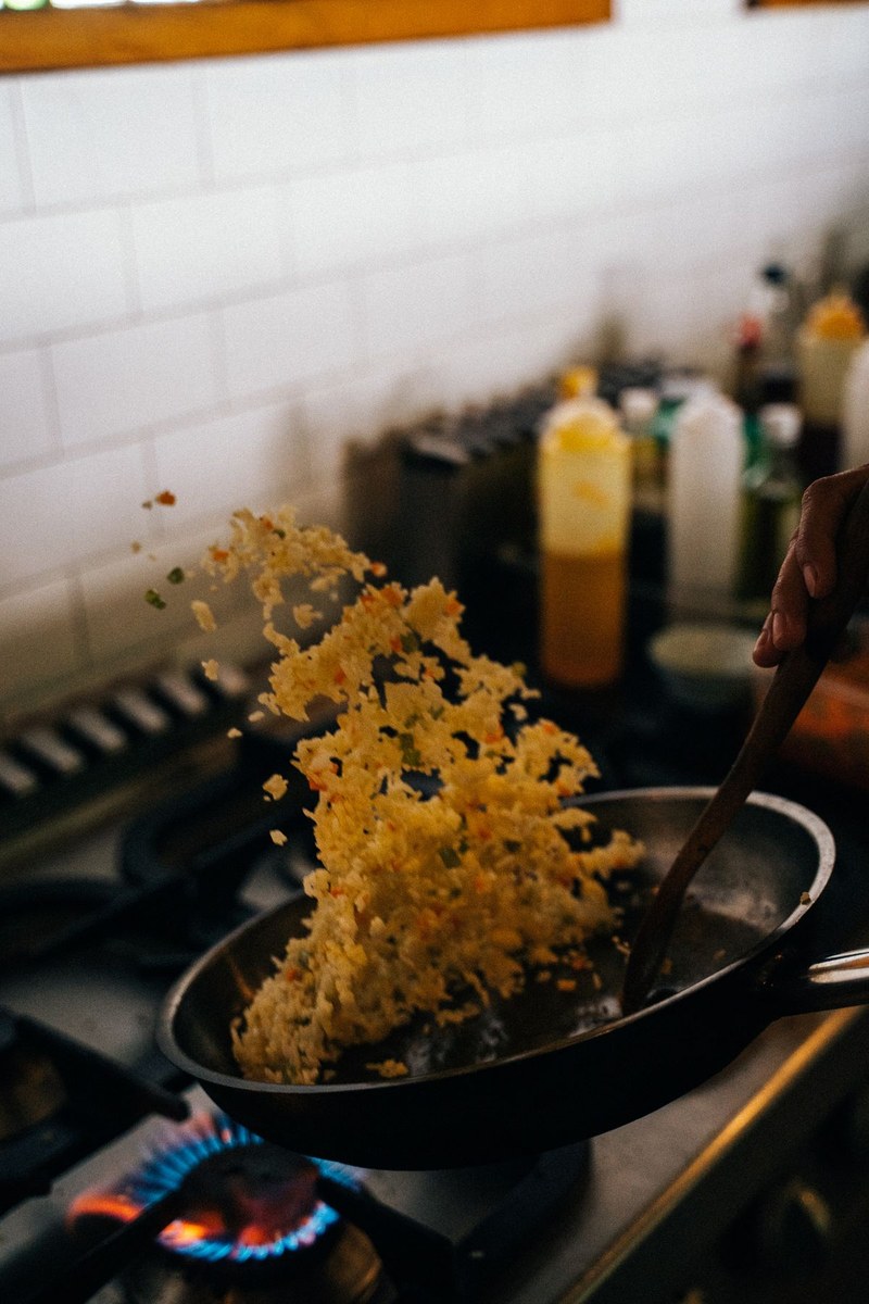 Chef tossing fried rice in a pan over a high gas flame