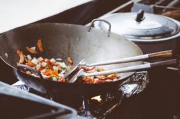 Colorful stir-fry vegetables cooking in a wok over a gas flame