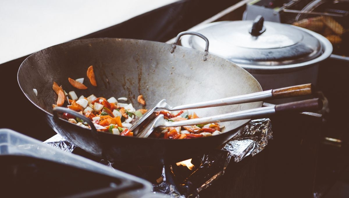 Colorful stir-fry vegetables cooking in a wok over a gas flame